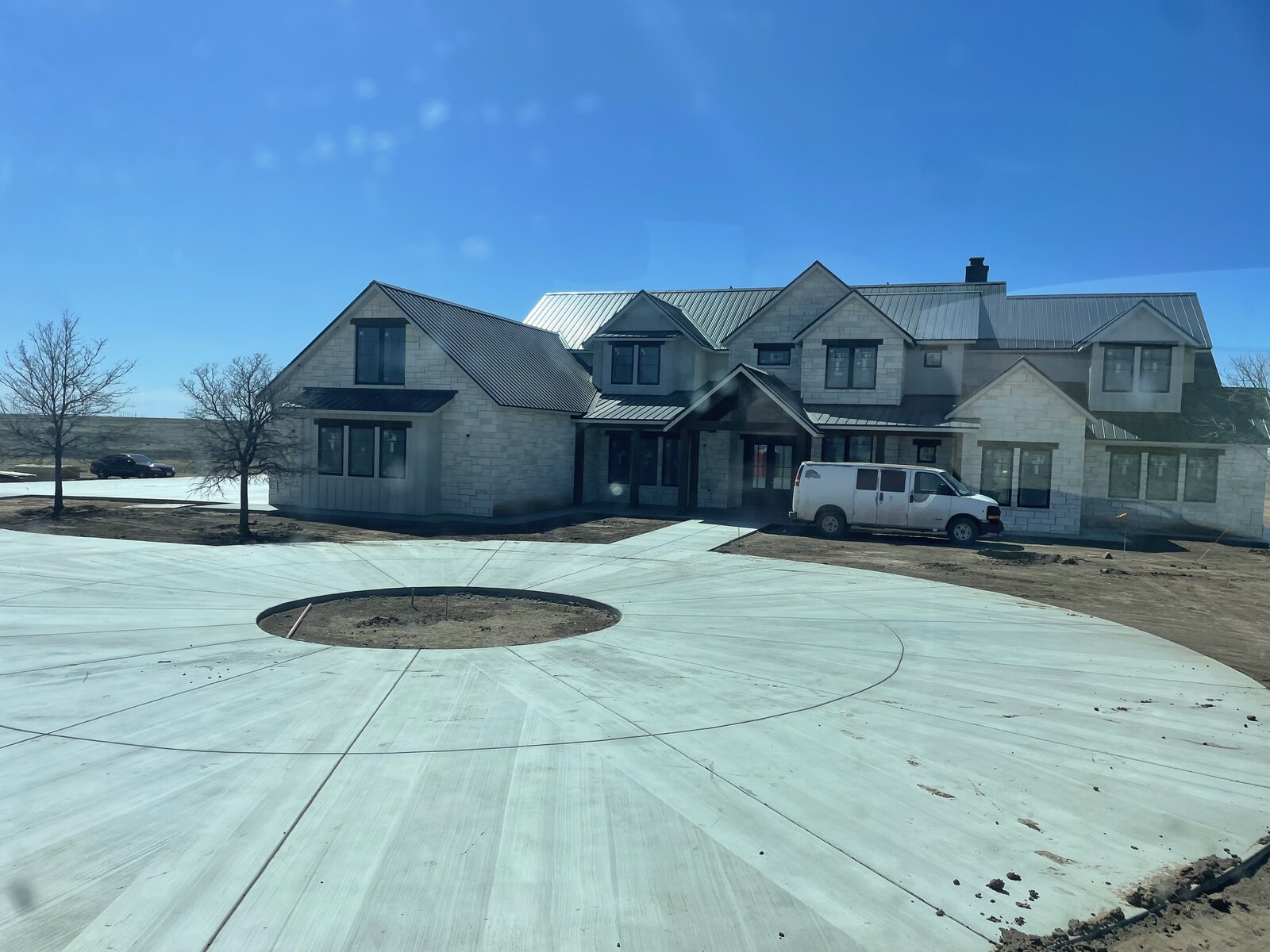 Stone home circular driveway, empty tree bed